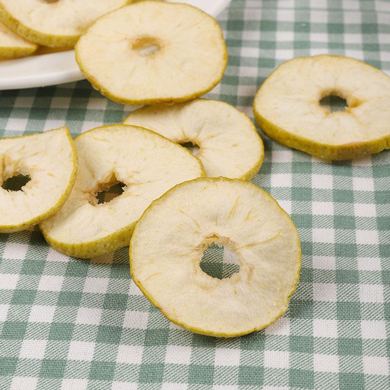 Vacuum fried green apple slice close up, vivid green skin edge and crispy pale flesh detail