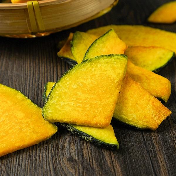Vacuum fried pumpkin slices stack display, abundant crispy half moon chips